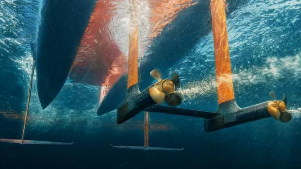 Underwater view of a MobyFly electric pod motor and propeller mounted on an orange foil strut, with the hull above the surface.