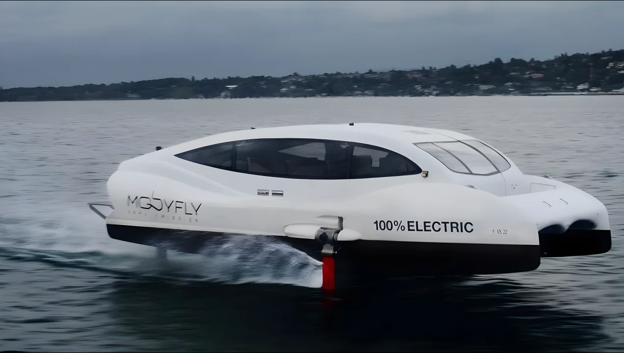 The MBFY-10 prototype hydrofoil demonstrator on its foils, marked 100% ELECTRIC, running on a lake under an overcast sky.