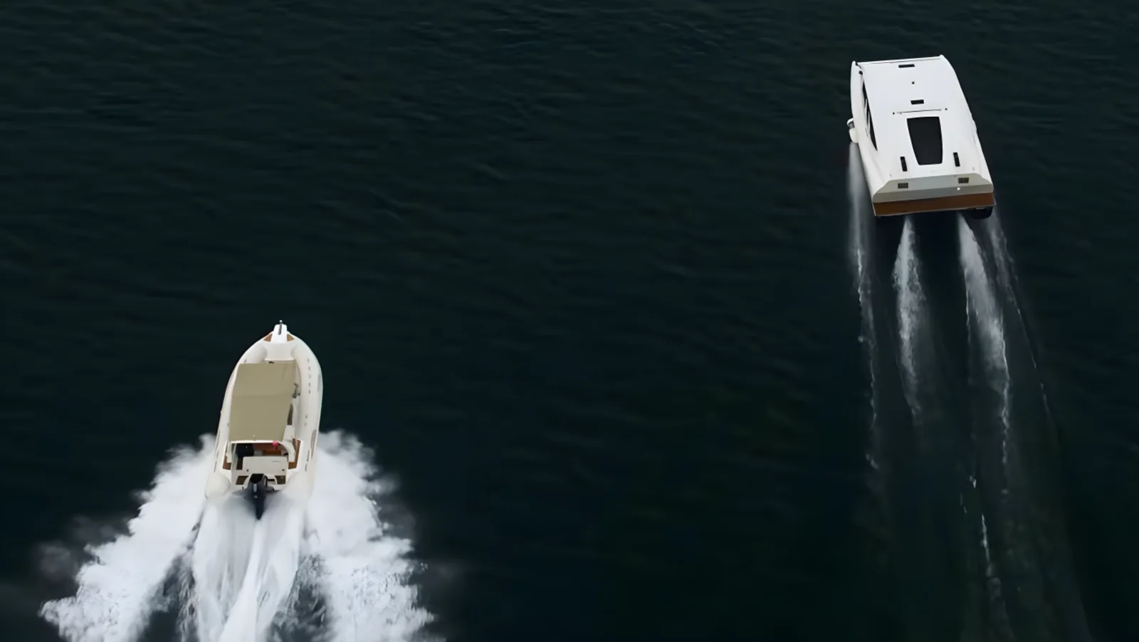 Aerial view of a MobyFly vessel on foils leaving an almost invisible wake while a smaller RIB beside it cuts a large white wake.